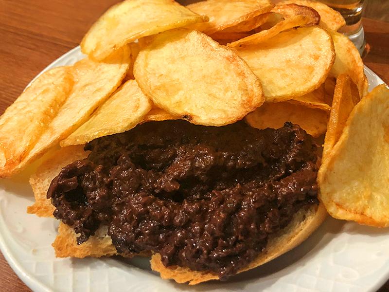 Tapa tradicional de morcilla de León sobre pan con patatas fritas en el Mesón Jabugo, lugar clave para ir de tapas por León.