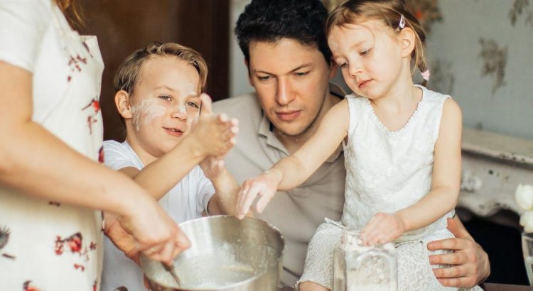Niños cocinando recetas dulces caseras en la cocina junto a sus padres.